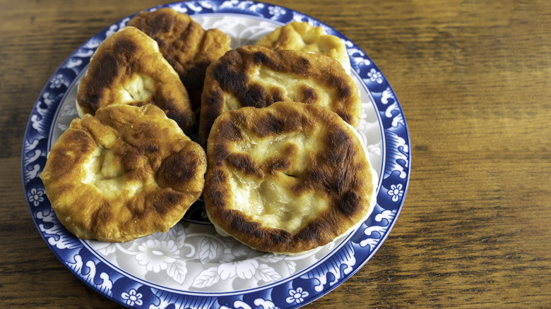Navajo fry bread, with a pillowy texture and a golden brown color, on a blue and white plate