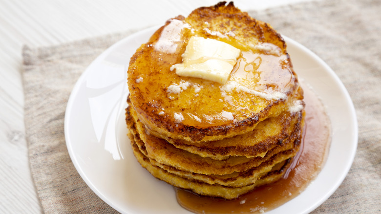 Johnnycakes covered in butter and syrup on a white plate