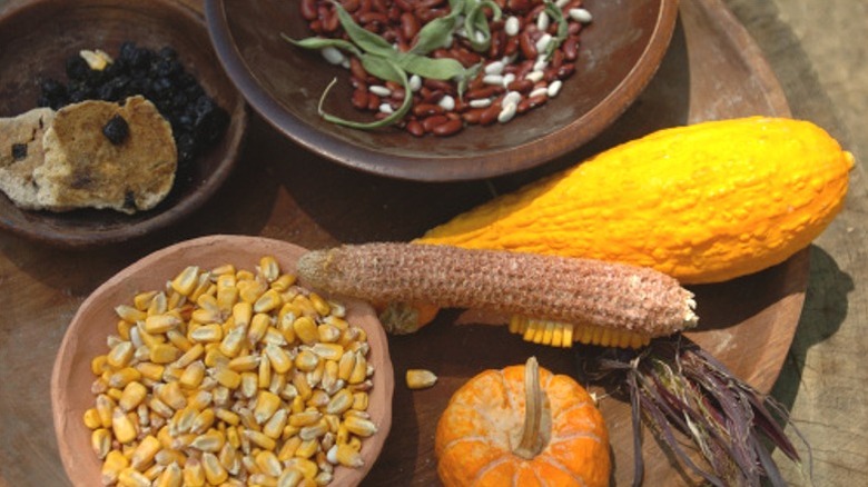 Corn, squash, and beans for a traditional three sisters soup, in wooden and earthenware bowls