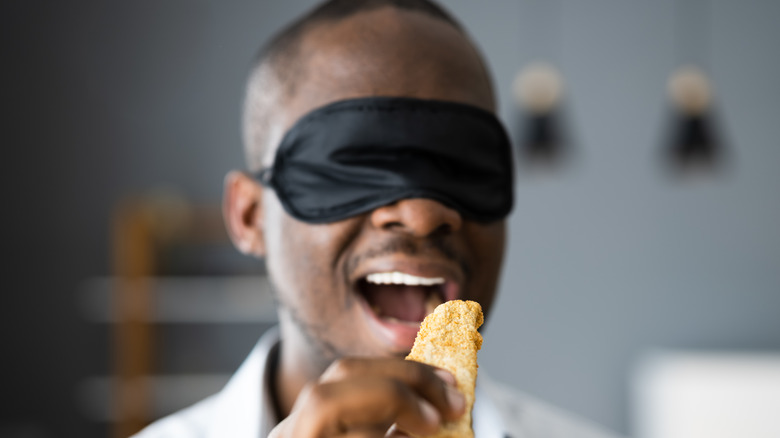 Man in blindfold tastes food