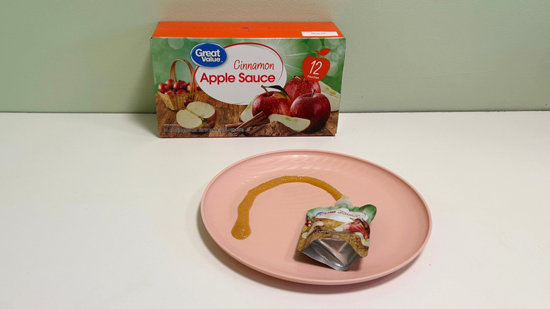 A box of Great Value Cinnamon Apple Sauce behind a plate with applesauce