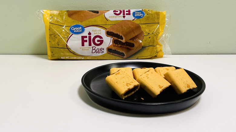 A bag of Great Value Fig Bars behind a black plate of Fig Bars