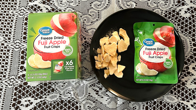 A box of Great Value Freeze Dried Apples beside a black plate of apple crisps