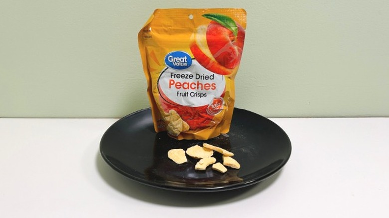 A bag of Great Value Freeze Dried Peaches Fruit Crisps on a plate beside some freeze dried fruit