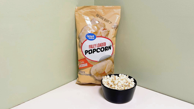 A  bag of Great Value Fully Loaded Popcorn beside a black bowl of popcorn