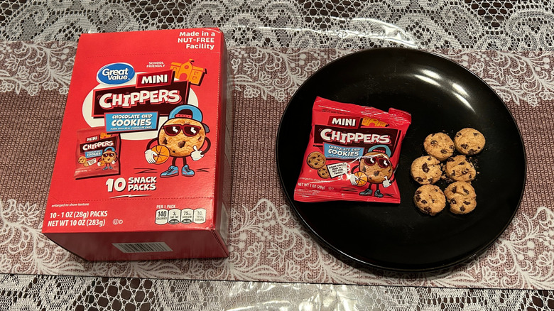 A box of Great Value Mini Chippers beside a black plate with mini chocolate chip cookies