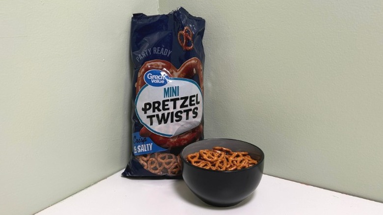 A bag of Great Value Mini Pretzel Twists behind a black bowl of pretzels