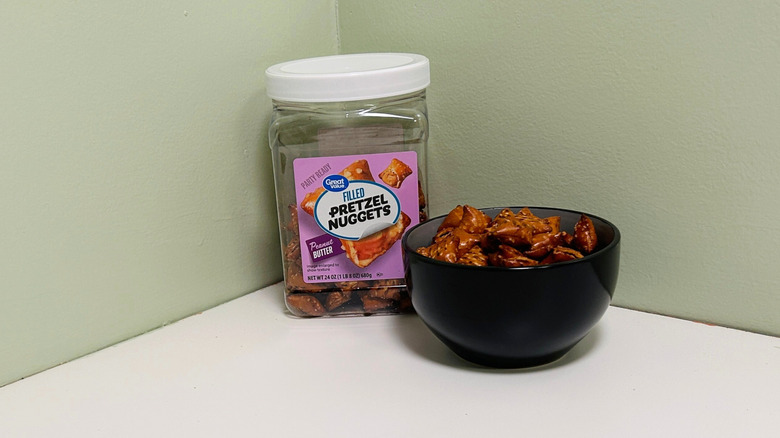 A plastic jar of Great Value Peanut Butter Filled Pretzel Nuggets beside a bowl of pretzels