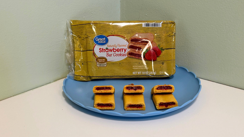A container of Great Value Strawberry Bar Cookies sits on a plate with bar cookies