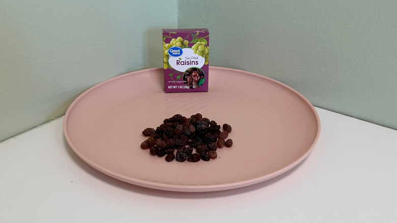 A box of Great Value Sun-Dried Raisins on a plate with raisins