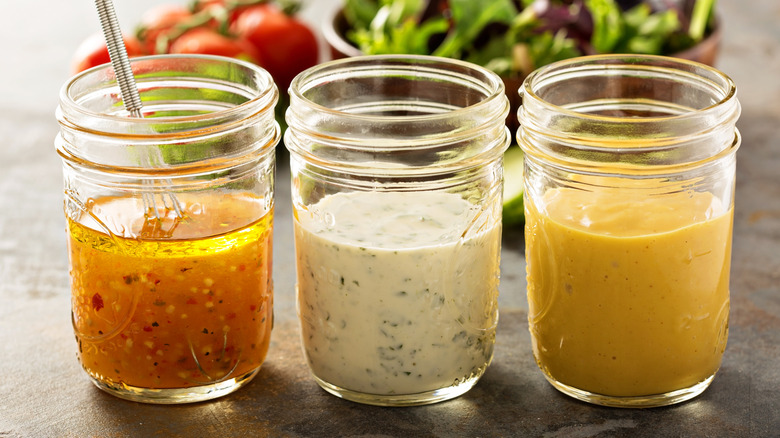 Three different homemade salad dressings in mason jars