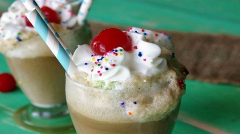 Mint chocolate chip root beer float topped with whipped cream, sprinkles, and a cherry