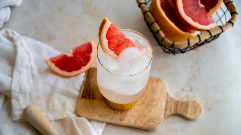 A sparkling paloma in a glass with ice and a pink grapefruit wedge