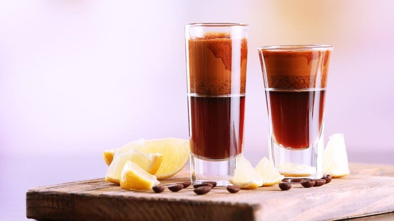 Two creamy Nutella shots in shotglasses, surrounded by lemon wedges and coffee beans