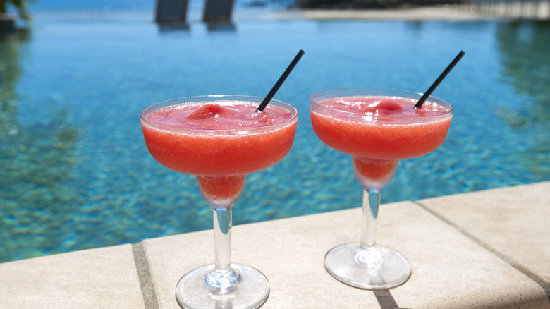 Two bright red strawberry daiquiris by the poolside
