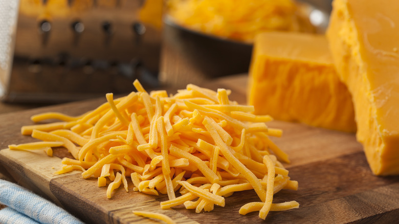 Shredded cheese on cutting board