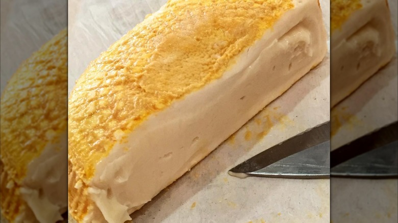 Half a wheel of a casinca cheese on a cutting board with a knife