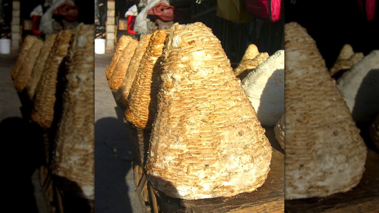 Multiple cones of shosha cheese at an outdoor market stall