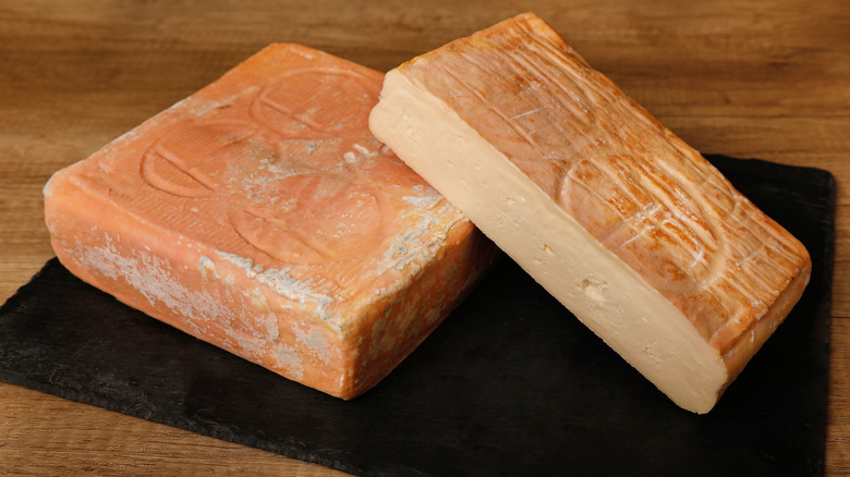 Whole and half squares of Taleggio cheese on a stone board