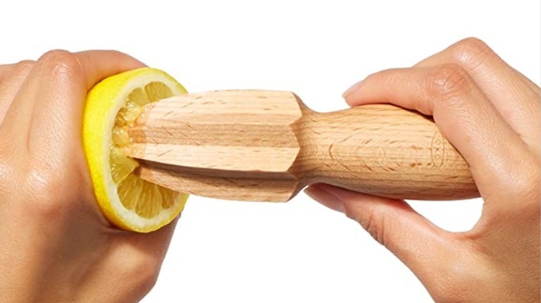 Hands using wooden lemon juicer