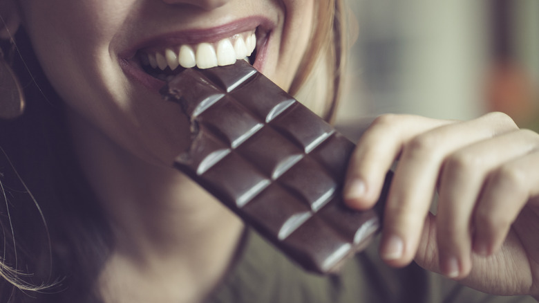 Woman biting into chocolate bar