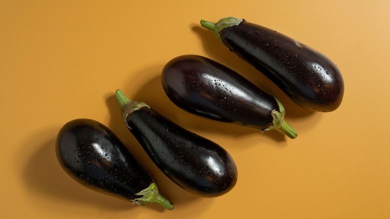 Assorted eggplants on orange backdrop