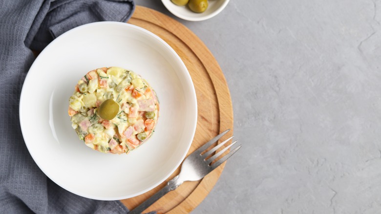 White plate of ensaladilla Rusa garnished with an olive