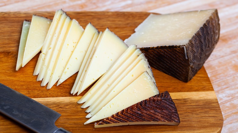 Slices of Manchego cheese on wooden cutting board