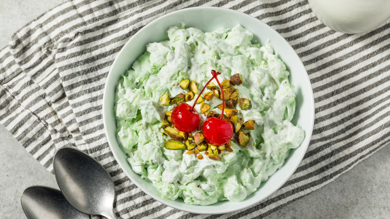 White bowl of Watergate Salad topped with maraschino cherries