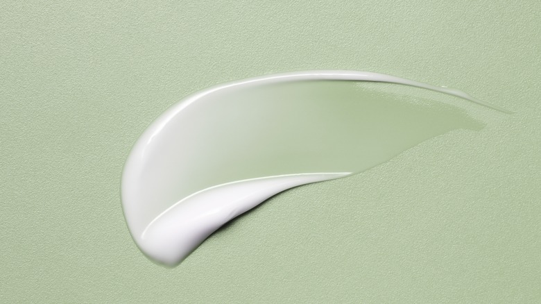 Face cream on green background