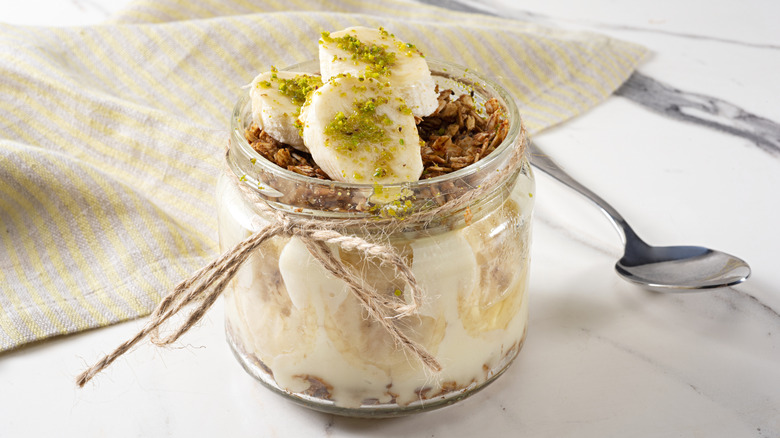 glass of banana pudding with granola and chopped pistachios