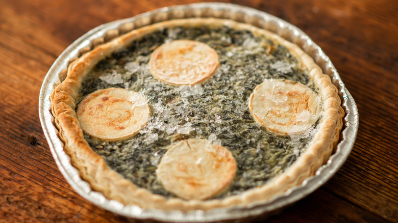 A frozen spinach quiche on a brown table