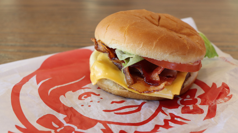 A junior bacon cheeseburger from Wendy's, somewhat sloppily assembled, with the beef patty almost completely hidden from view by cheese