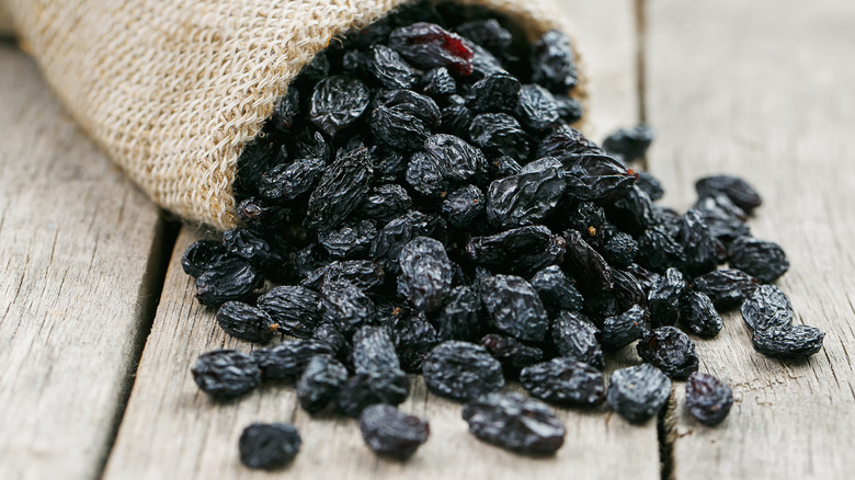 burlap sack of raisins spilling onto wooden table