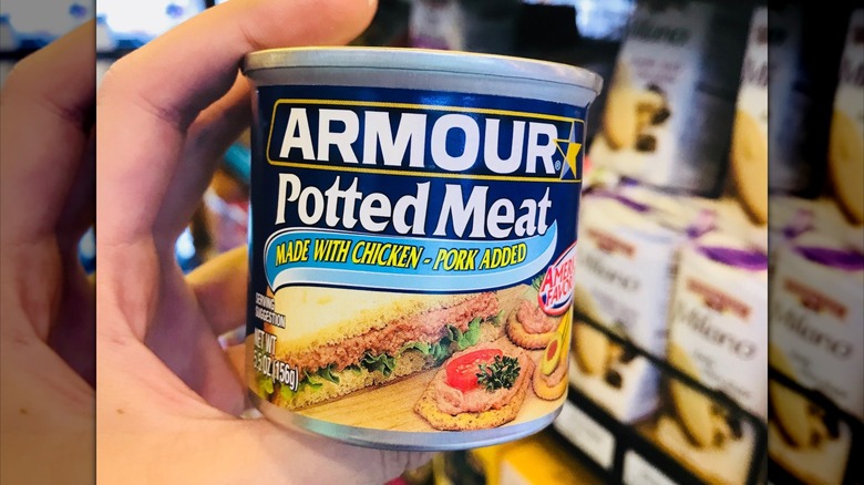 Hand holds Armour potted meat can in grocery store
