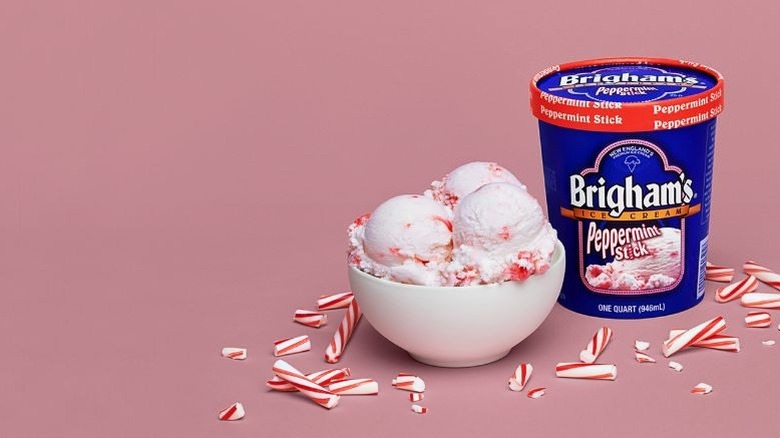 An ice cream pint next to a bowl against a pink background
