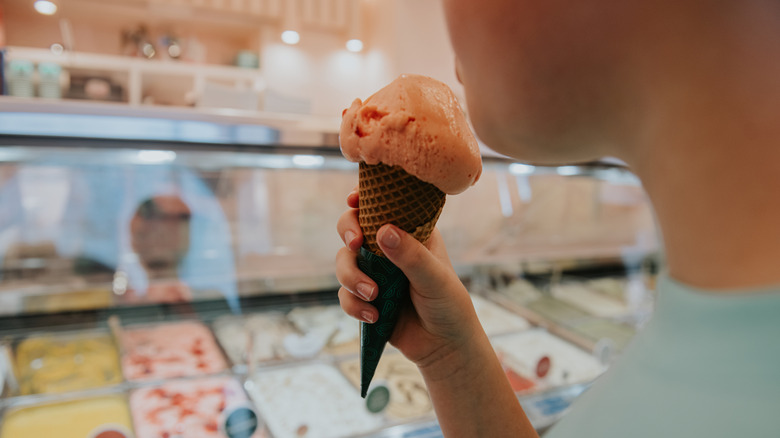 A child licks an ice cream cone in front of a store counter