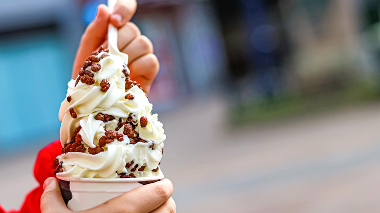 A person holding an ice cream cone with candy mixed in