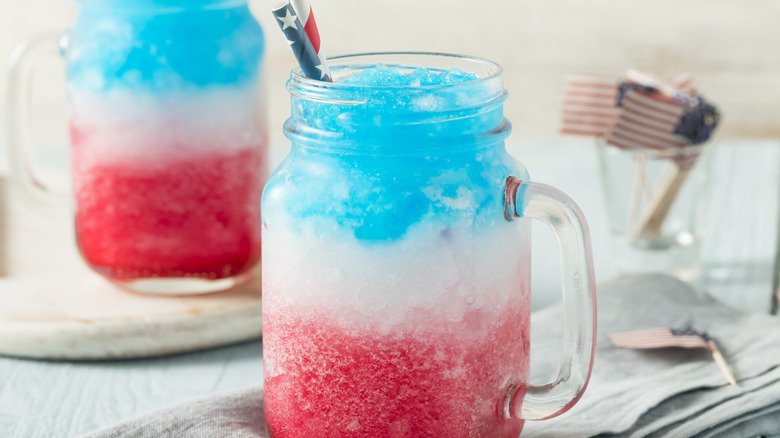 Homemade red, white, and blue slushie in mason jar with patriotic straw