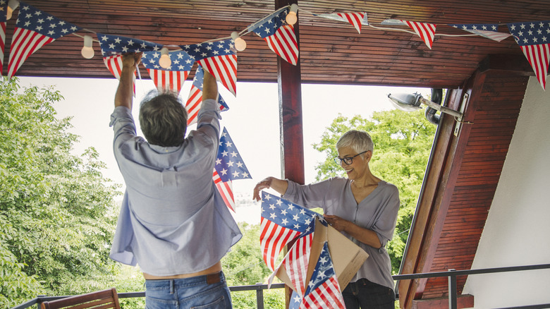 Couple hanging American flag banners in house
