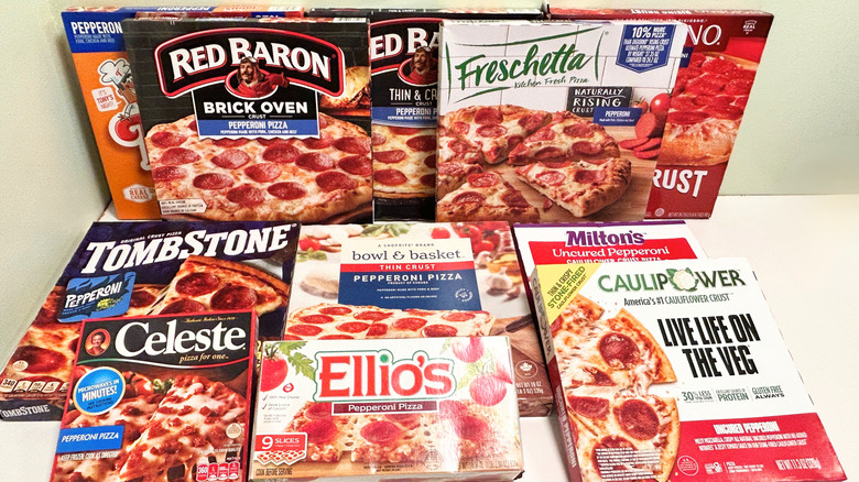 Several frozen pizzas stacked together against a green a white background