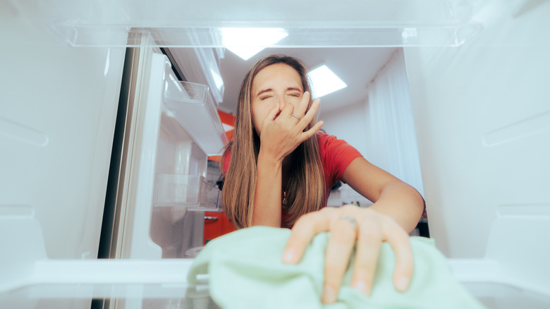 Person reacting to bad smell from open refrigerator