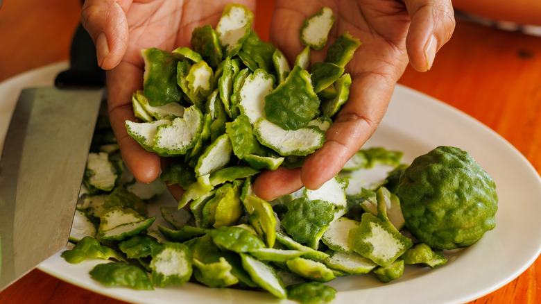 Gardener's hands holding chopped lime peel over a plate and knife