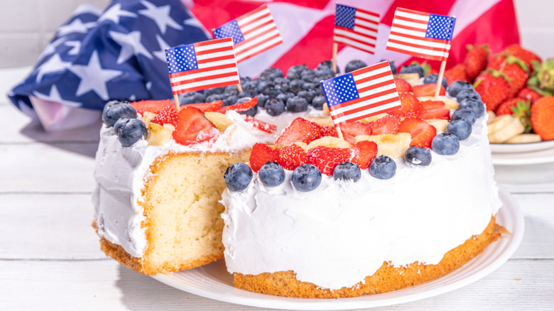 Cake with white frosting, blueberries, bananas, strawberries, and American flag toothpicks