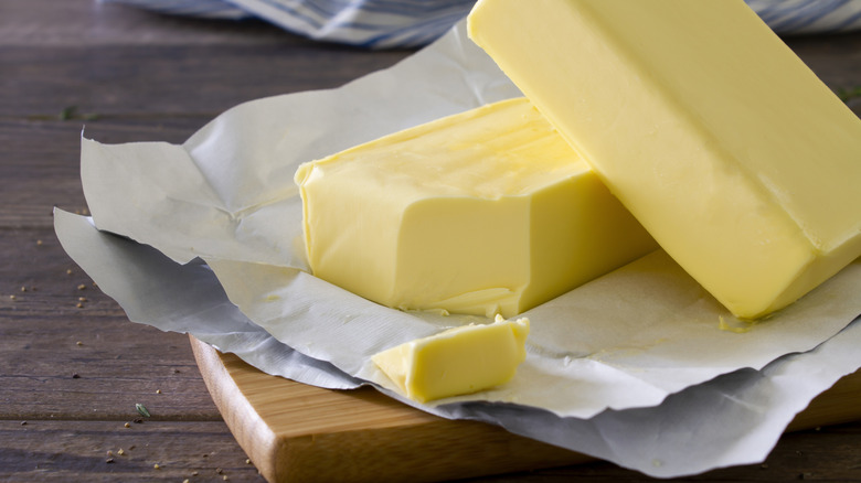 Two blocks of butter on a cutting board with parchment paper