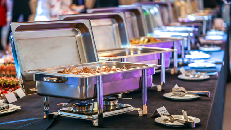 A buffet line with chafing dishes and labels for each food item