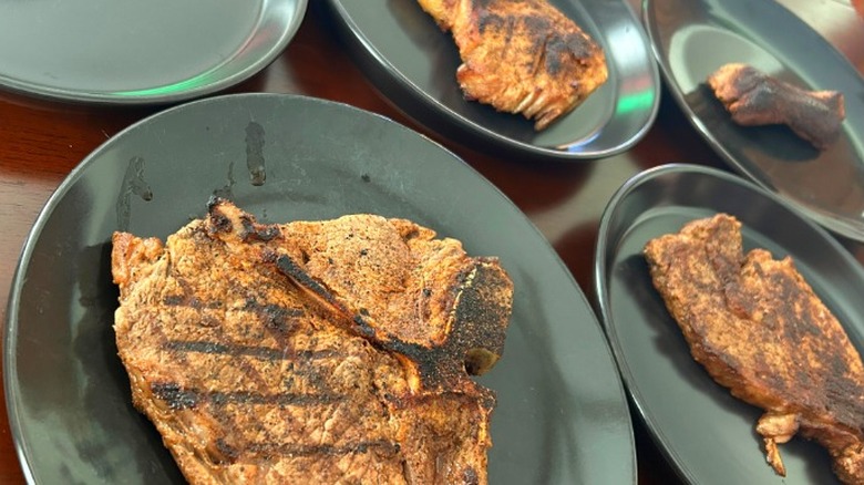 Close up of five different cuts of steaks on black plates