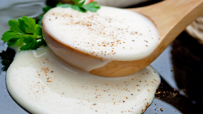 close-up shot of white béchamel sauce in a wooden spoon