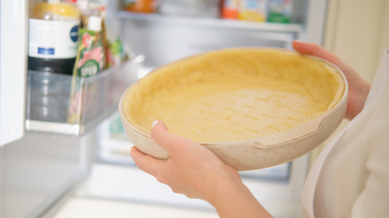 Person holds pie crust next to fridge