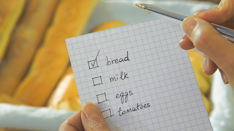 Person checking off grocery list in store